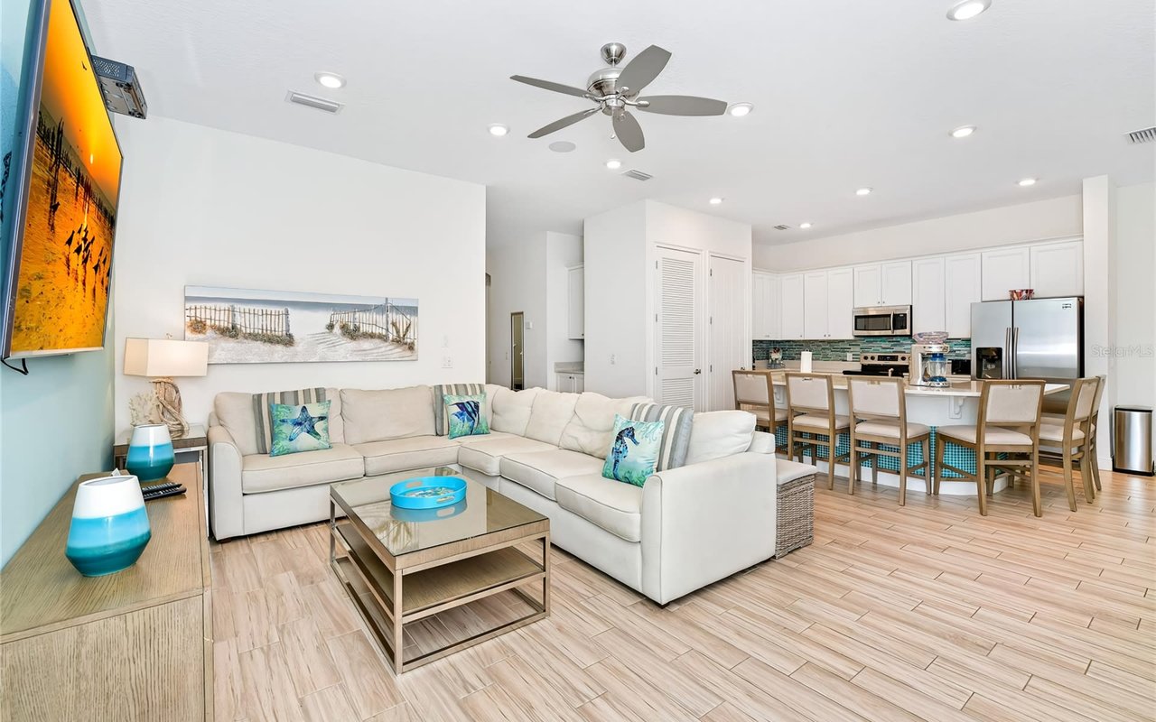 A modern aesthetic living room with a coffee table,  a couch, and a small kitchen area with dining tables and chairs.