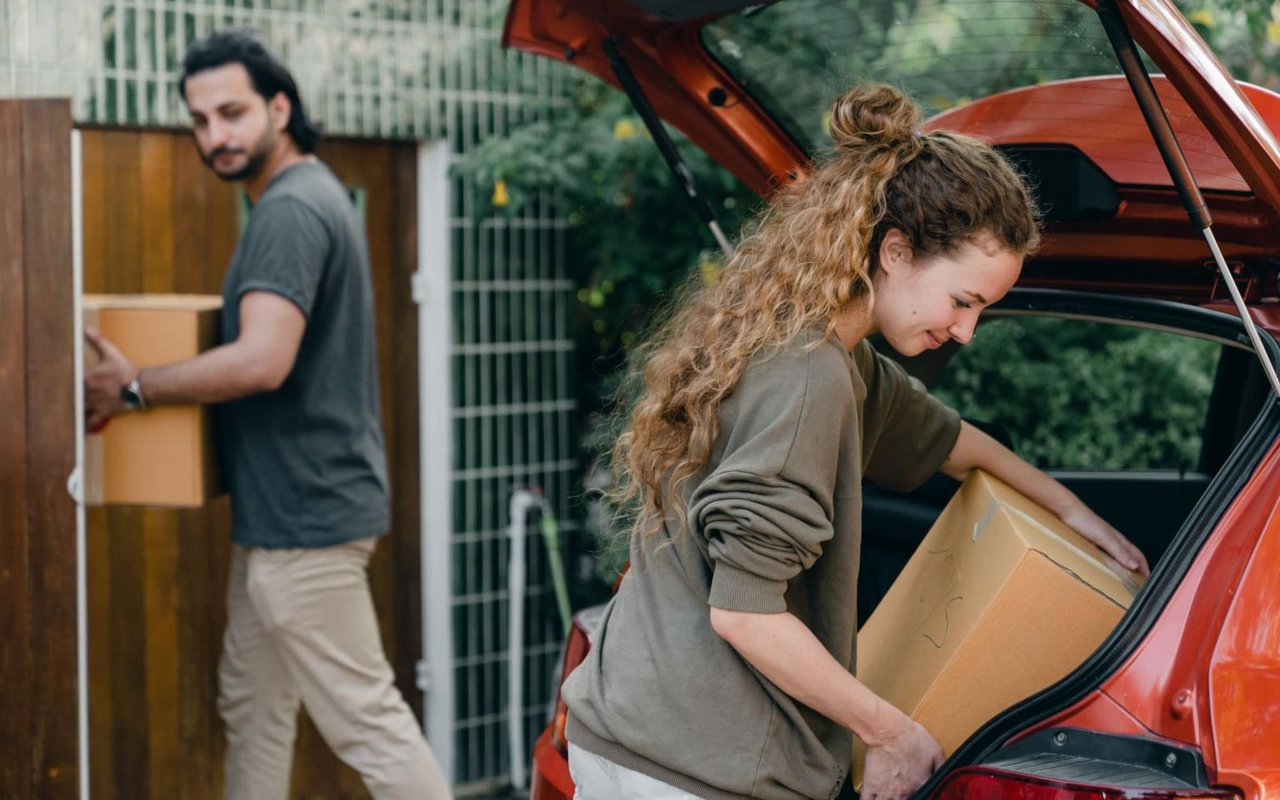 Couple unloading cardboard boxes from a car during a move.