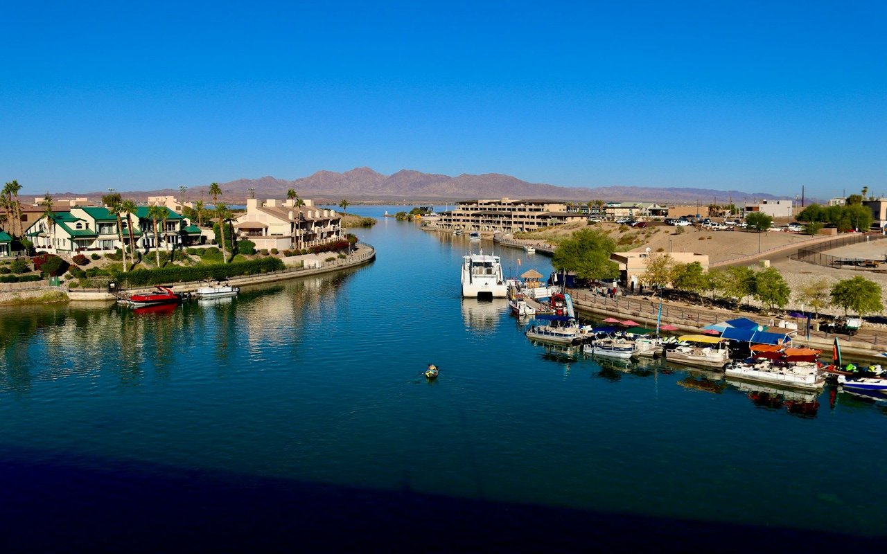 Scenic waterfront view with boats, buildings, and mountains, perfect for luxury homes or townhomes with waterfront access.