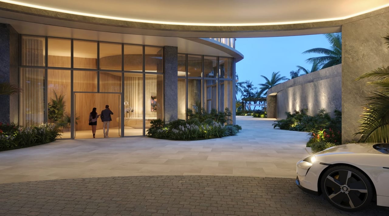 Rivage Bal Harbour entrance with a curved glass lobby and landscaped driveway at dusk.