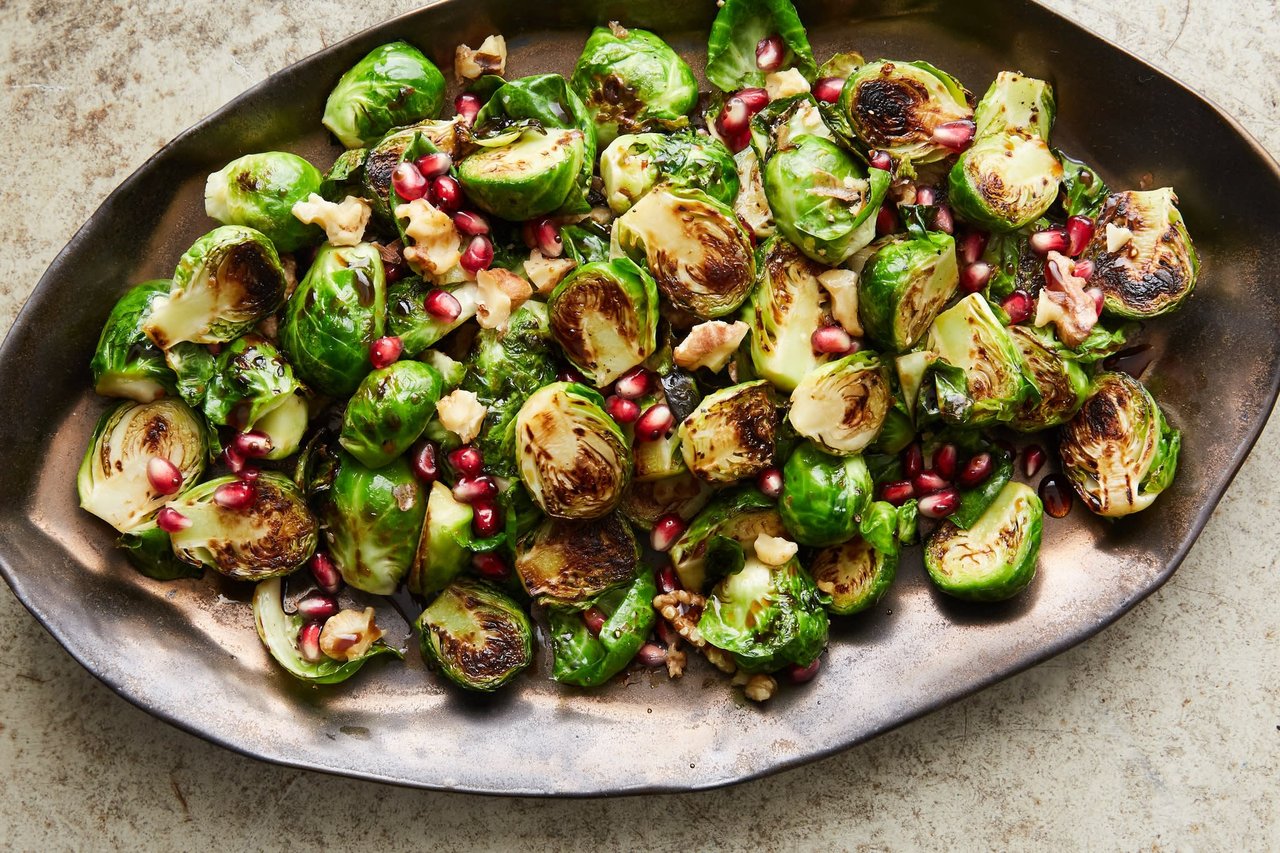 Roasted Brussels sprouts with pomegranate seeds and walnuts on an oval platter.