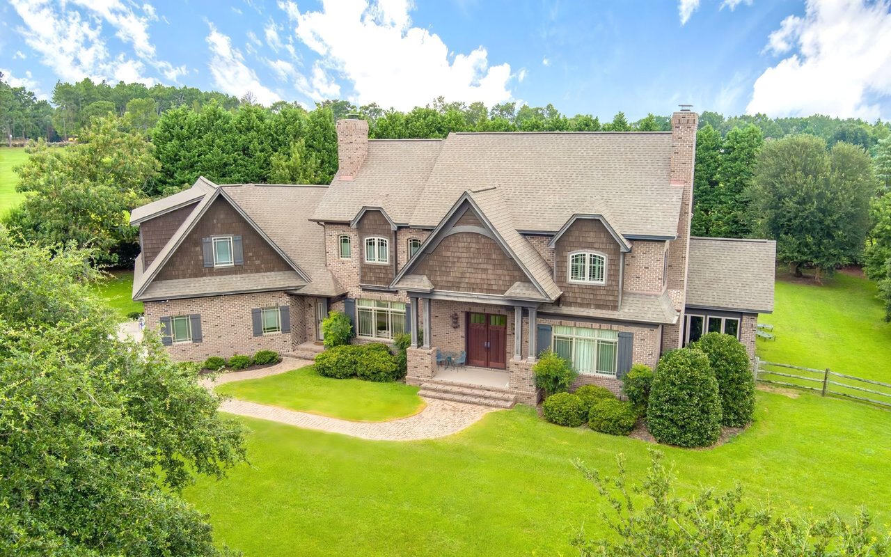 A large, two-story brick house with a gray shingled roof. 