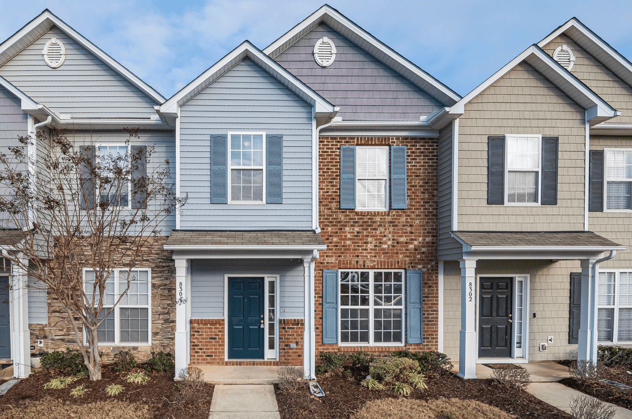 A row of colorful attached houses with brick exteriors and dormer windows.