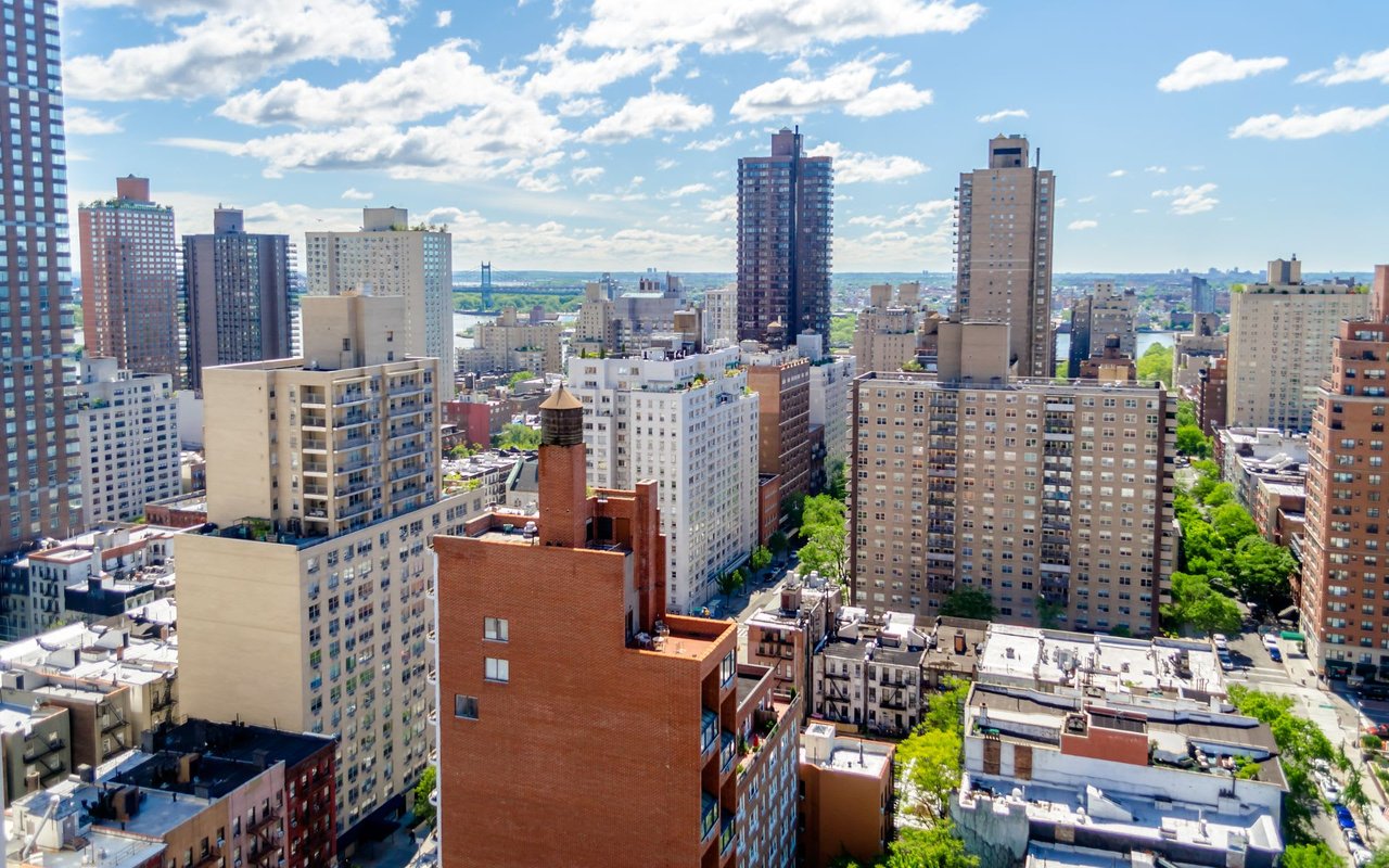 Aerial view of a cityscape with skyscrapers and a water tower in the distance.