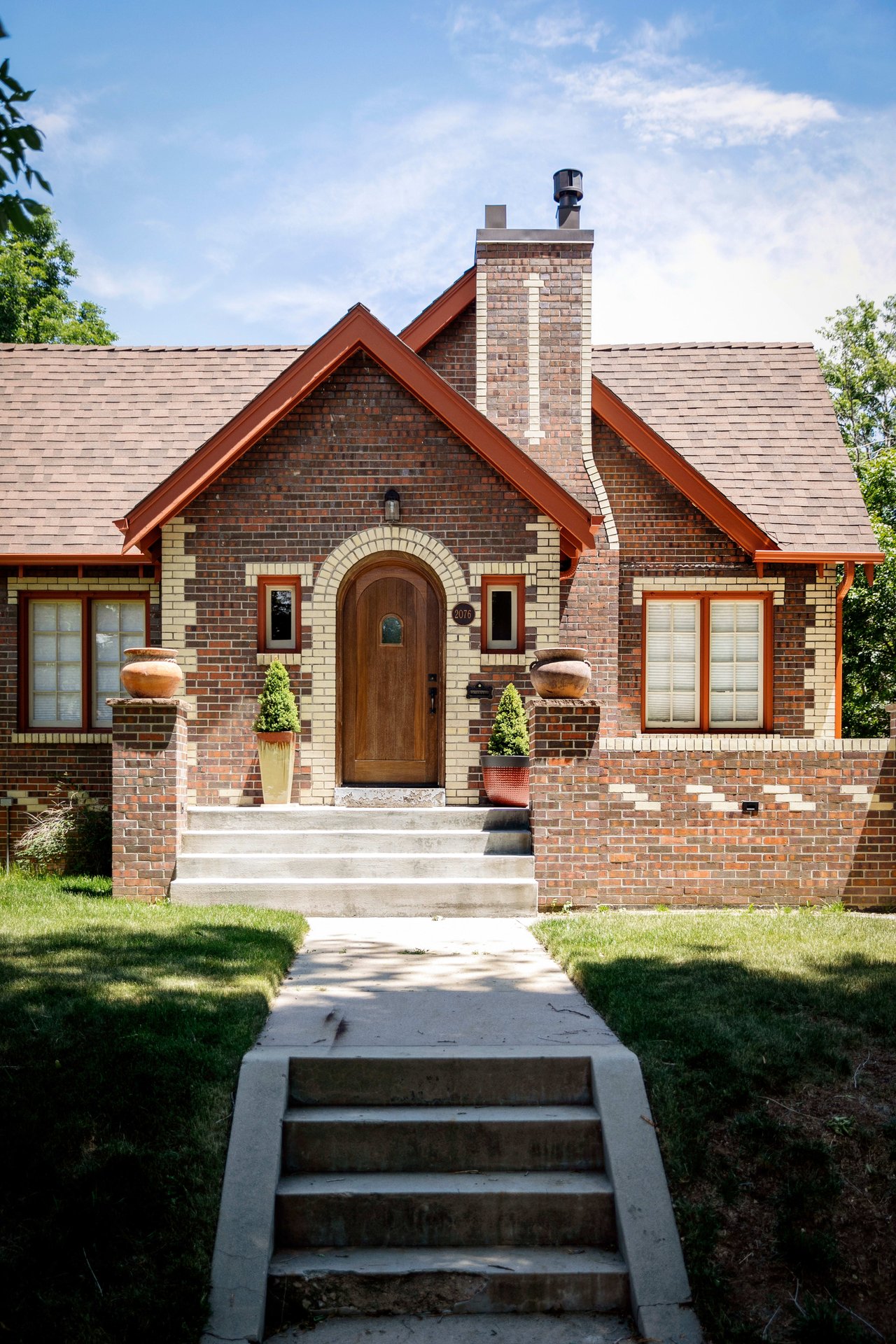 A brick house with a wooden front door and stairs leading up to it.