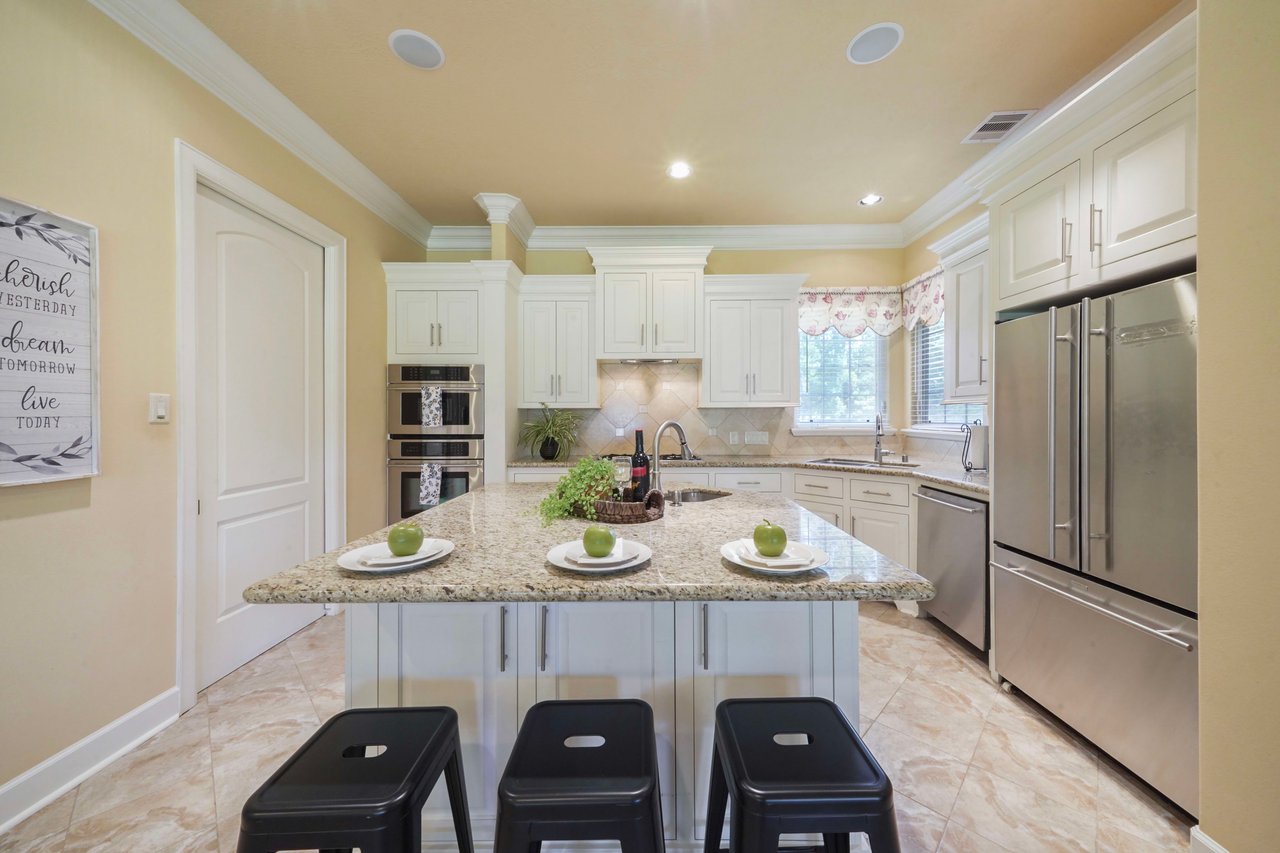 Kitchen offers ample cabinetry, corner sink with window, gas cooktop, large breakfast bar with prep sink & beverage fridge. The sliding door is to the walk-in pantry.