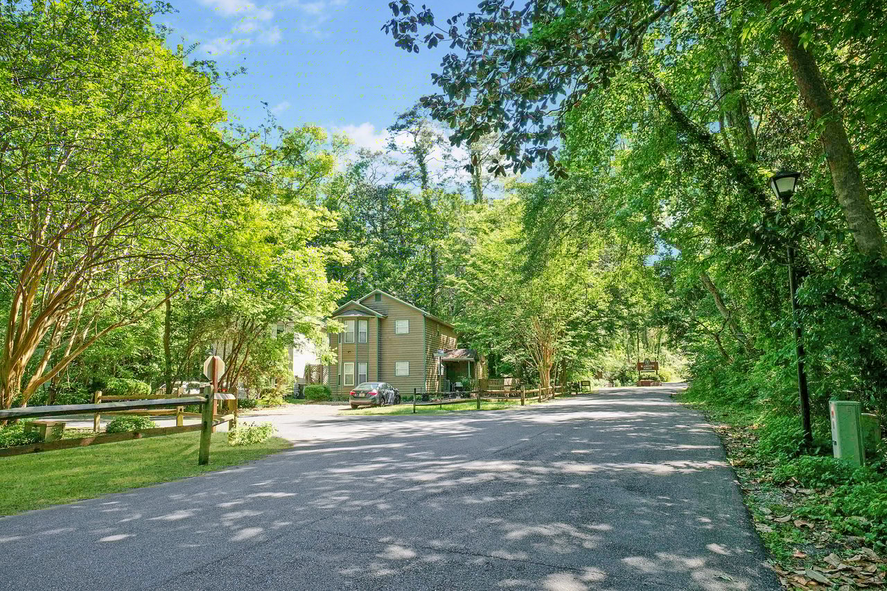 A street-level view within Blairstone Forest, highlighting houses, trees, and a peaceful neighborhood street.