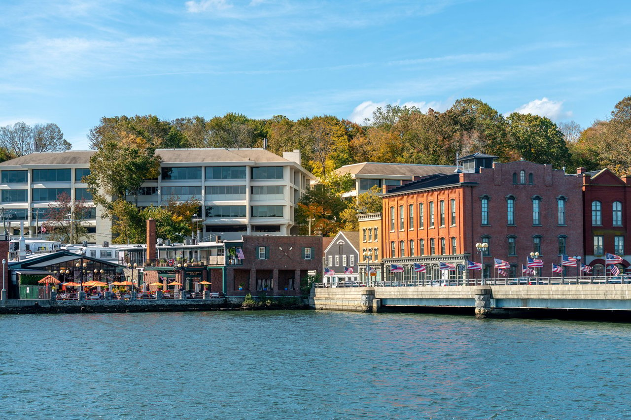 A view of a town from the water. The town is located on a river, and there are buildings beside the river.