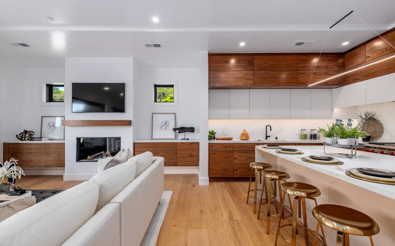 Open-plan kitchen and living room with walnut cabinetry, a white sofa and a kitchen island.
