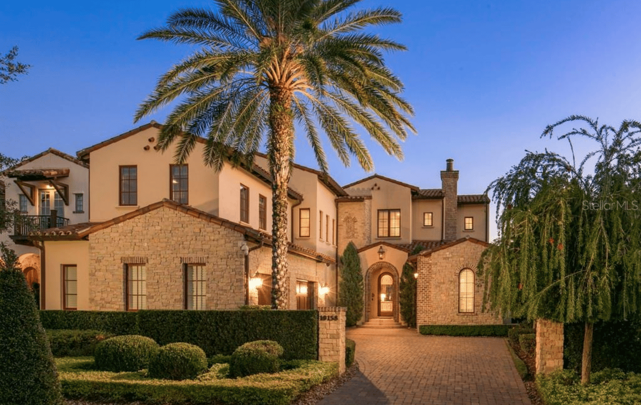 A large house with a driveway, a front lawn, and a palm tree in front of Golden Oak at Walt Disney World Resort, Florida.