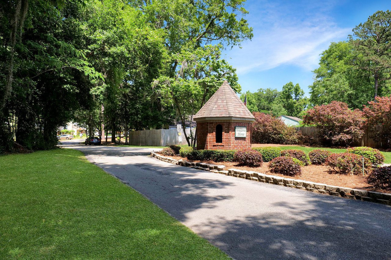 A ground-level view of a street in the Chases Ridge community, showing a tree-lined driveway leading to a house with well-maintained landscaping.