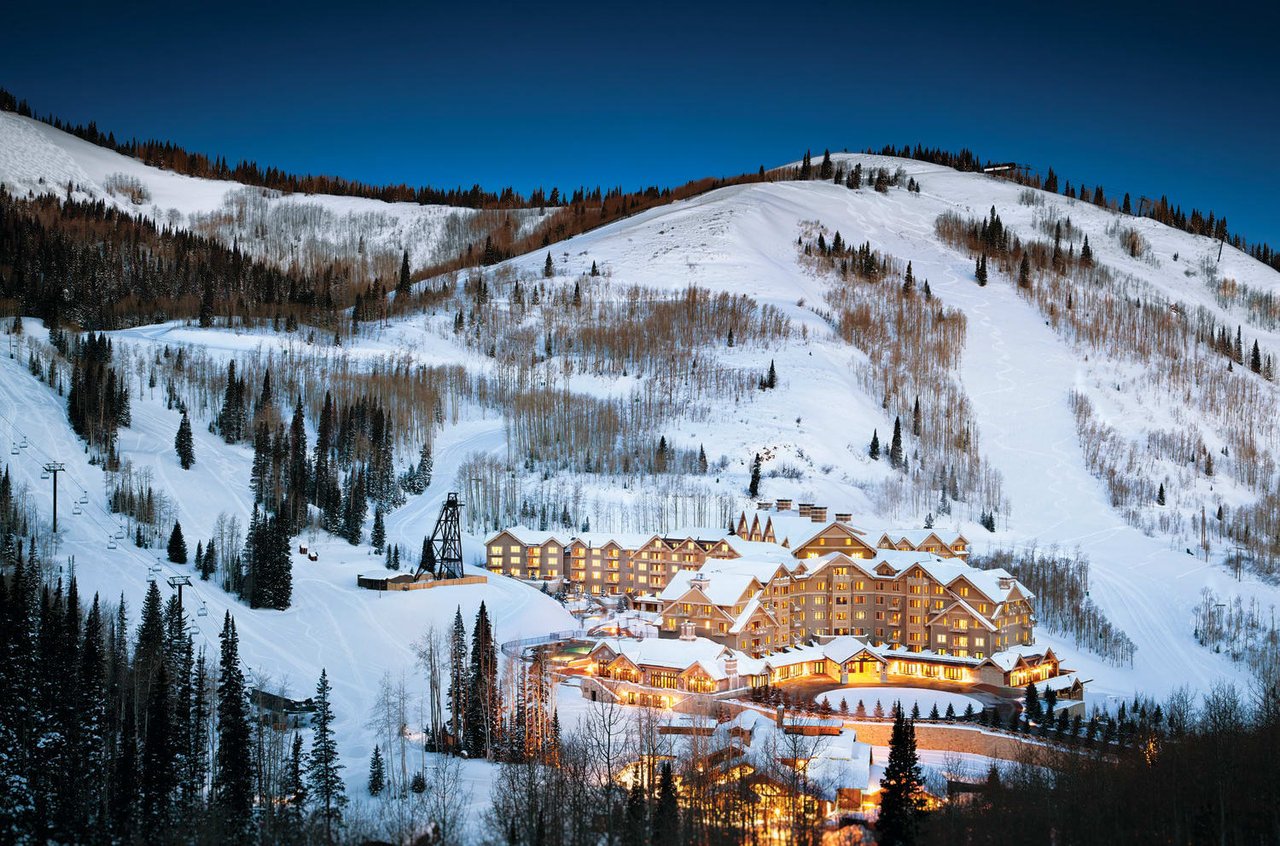 A ski resort with illuminated buildings nestled on a snow-covered mountainside at night