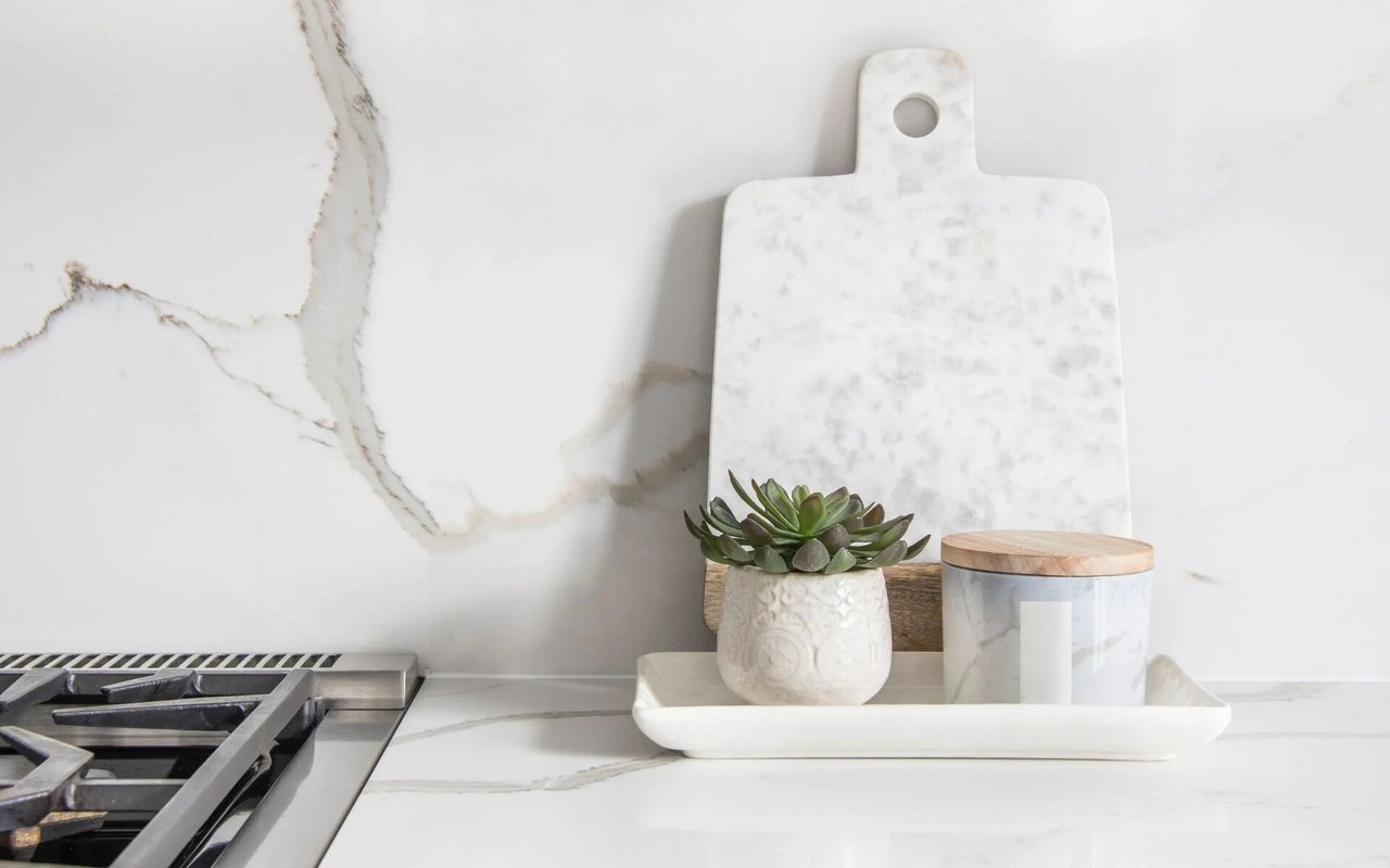 Bright kitchen with veined marble surfaces, a gas cooktop, and a succulent on the counter.