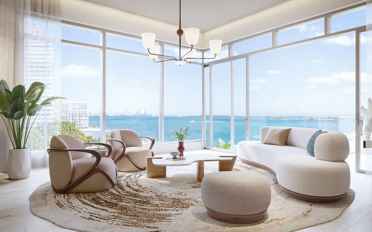 Living room with sculptural cream seating and floor-to-ceiling windows overlooking turquoise water.