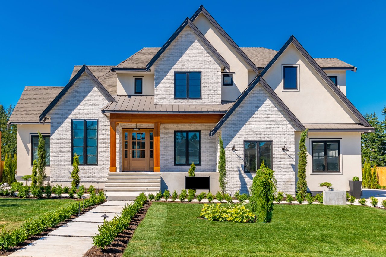 A close-up of a large white house with black shutters and a gray slate roof.