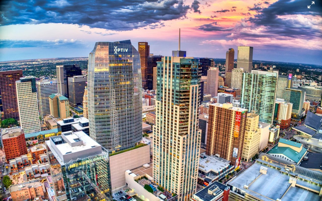  An expansive aerial shot showcases a vibrant city skyline under a dramatic sunset sky.