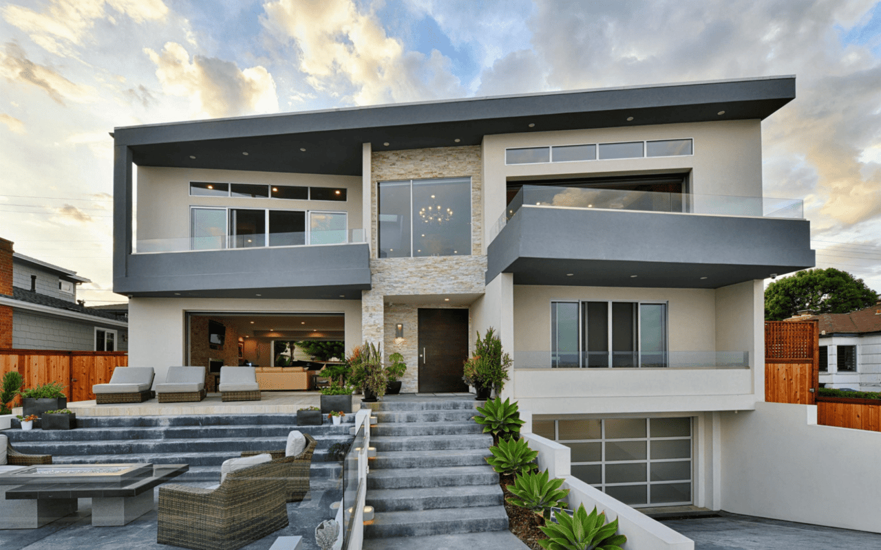 A striking modern multi-story house with a flat roof and a mix of light-colored stucco and stone cladding
