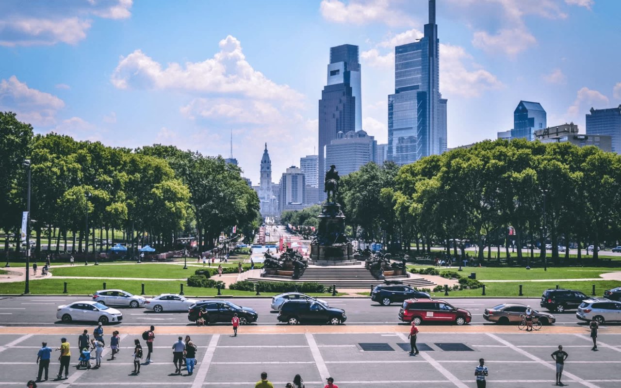 The Philadelphia skyline rises in the background, with tall skyscrapers piercing the clear blue sky.