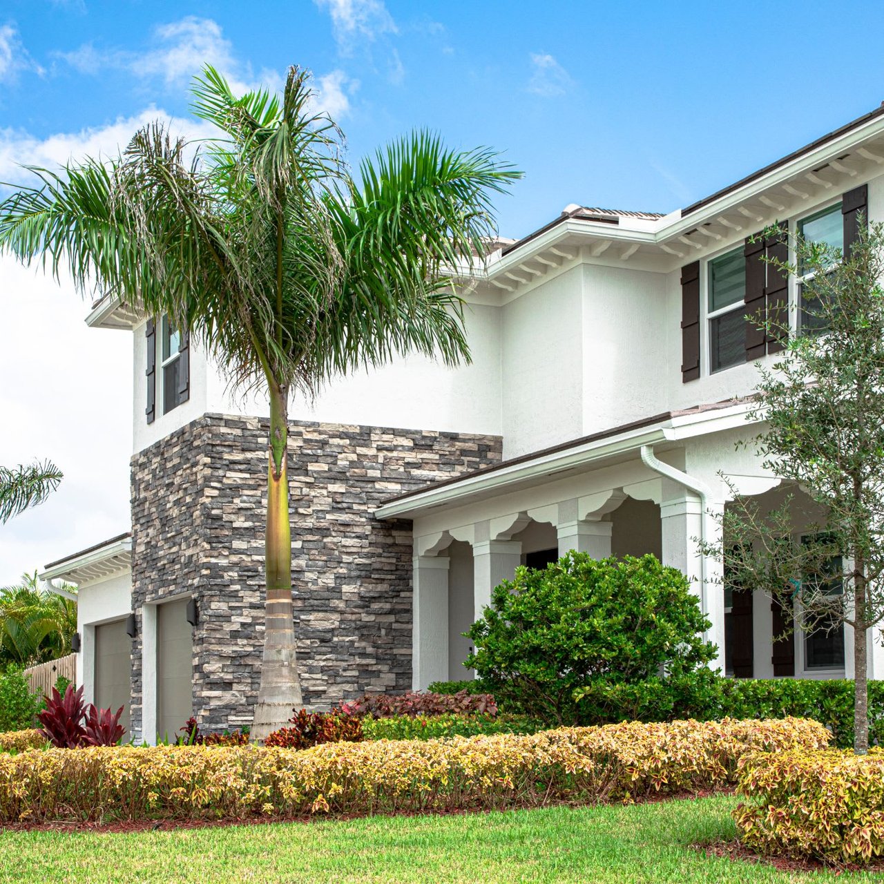  A modern two-story house with white stucco walls and dark brown window shutters.