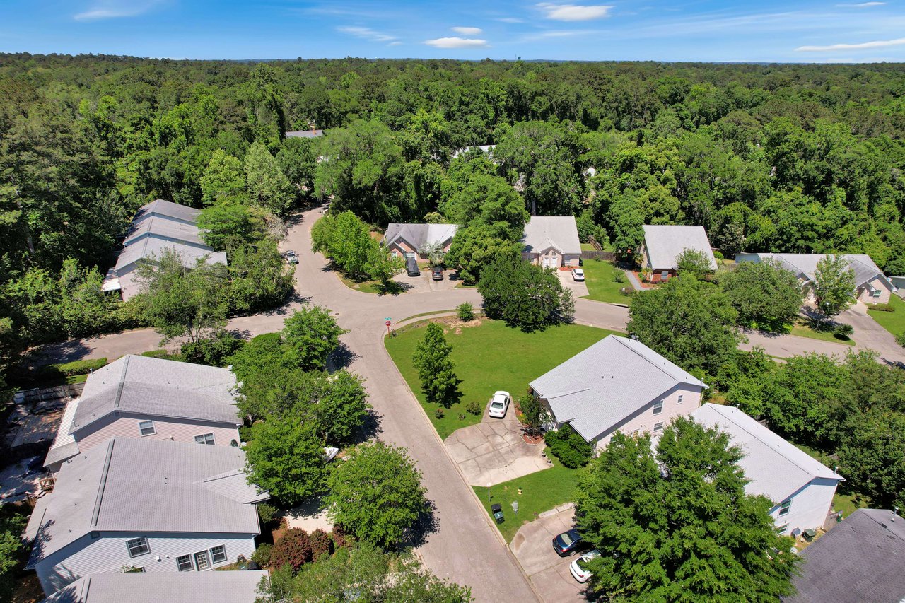 An aerial view of a residential area within the Sawgrass Plantation community, showing houses and streets with plenty of greenery.