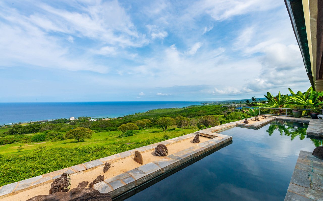 A large rectangular swimming pool with a view of the ocean