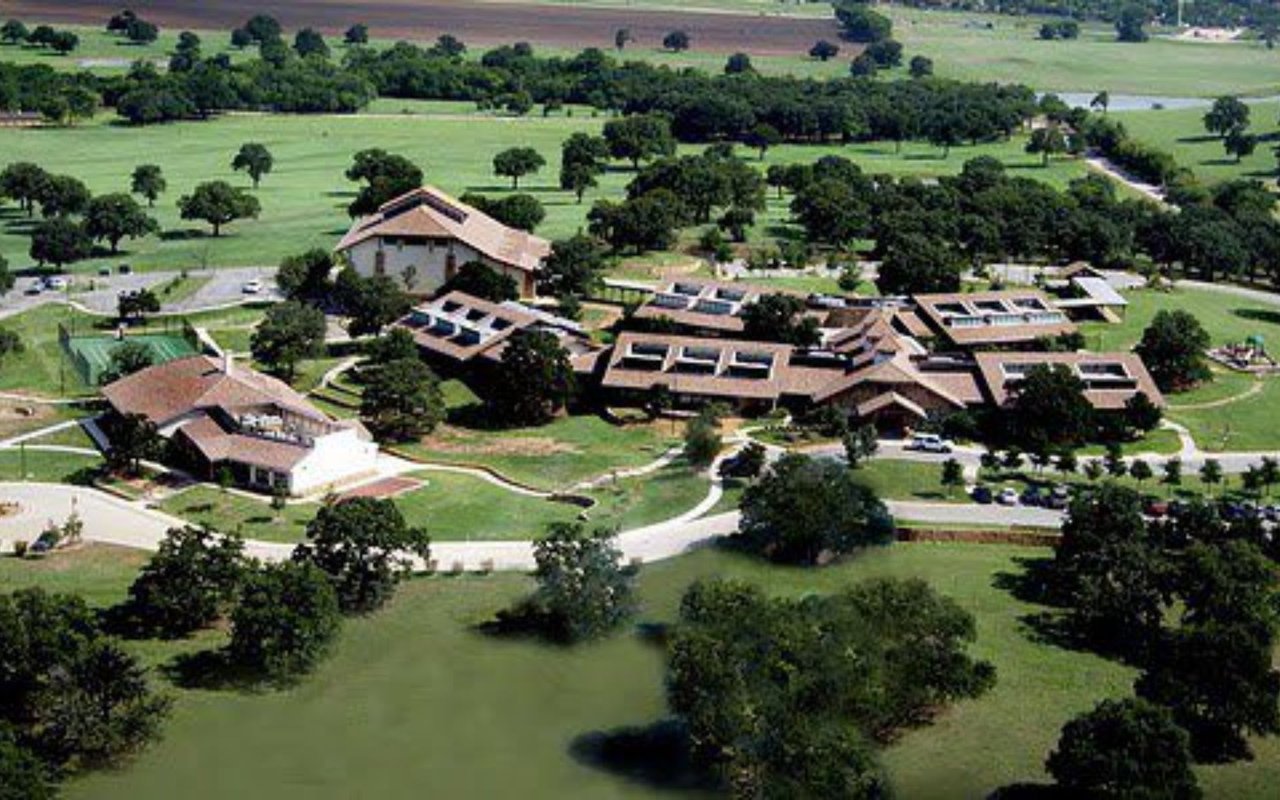 An aerial view of the buildings in a central green space, walking paths, and parking lots on the Westlake Academy campus.