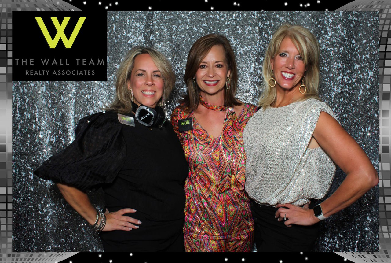 Three ladies wearing formal dresses in a photo booth