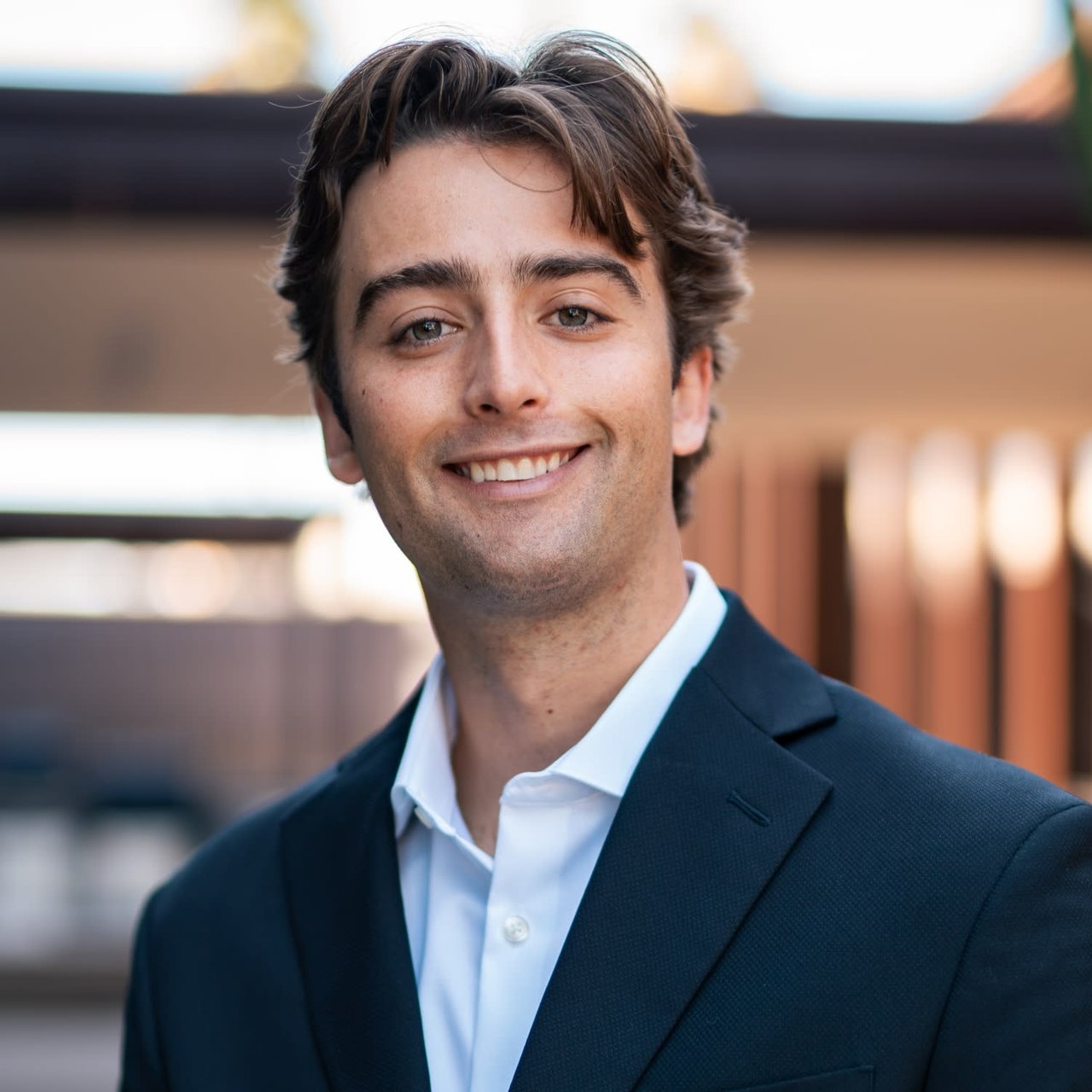 Nick George, a real estate professional from The Jenna Kaye Group, dressed in formal attire and smiling brightly.