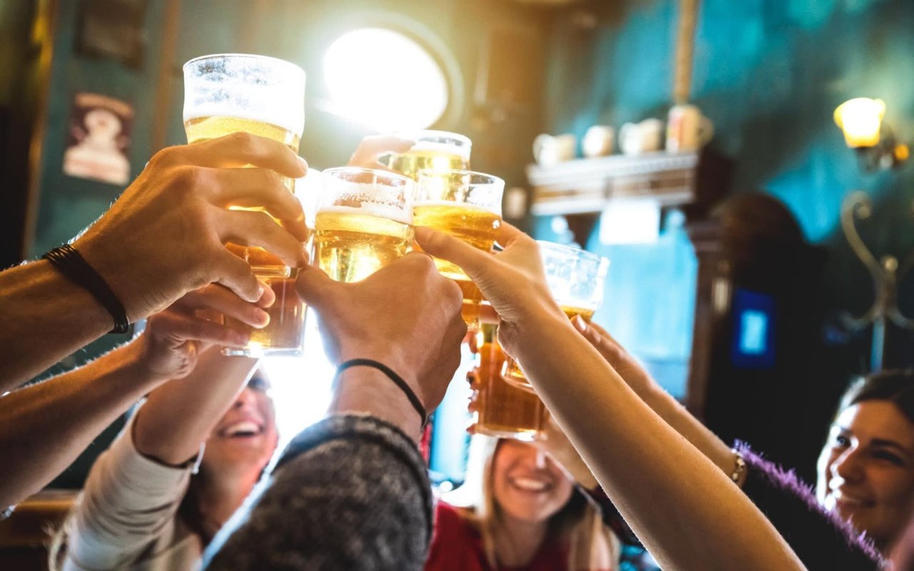 A group of people raising their glasses in celebration in a bar.