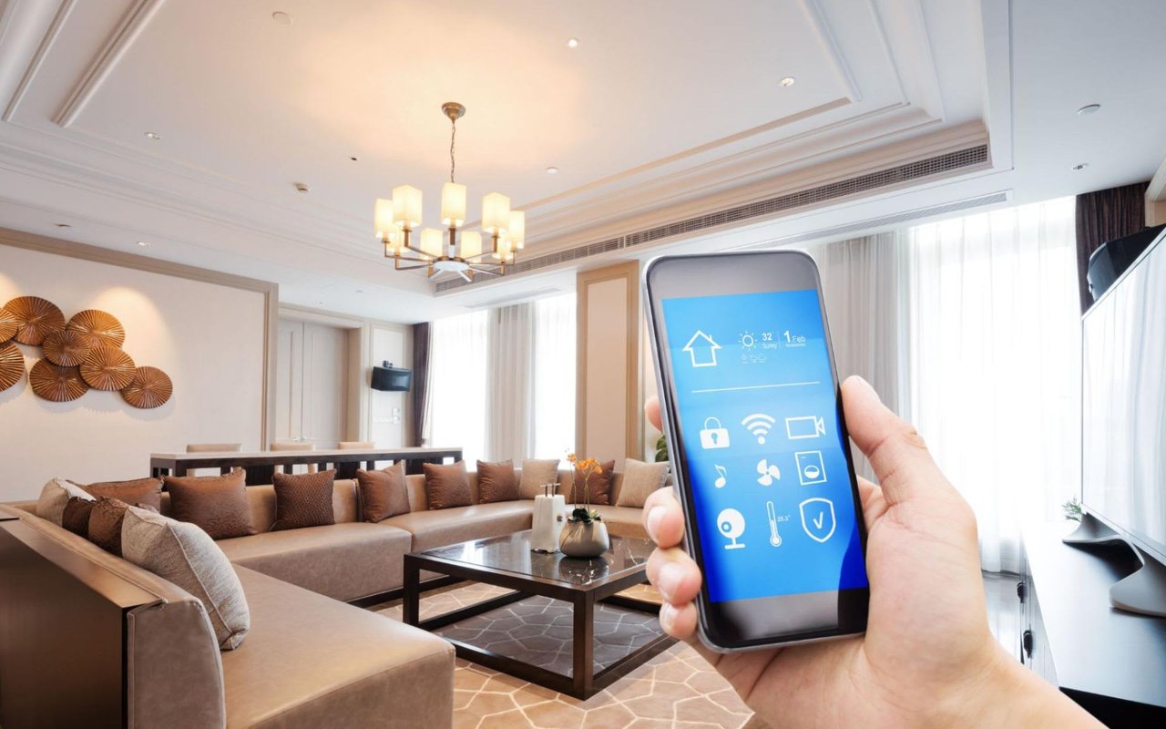 A close-up of a hand holding a smartphone in front of a living room.