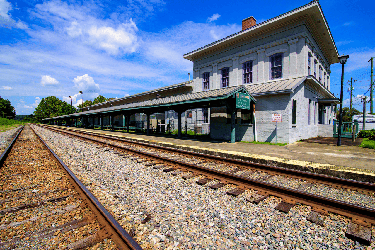 A historic train station with railroad tracks leading to it. The image captures a sense of history and transportation, likely representing a local landmark.