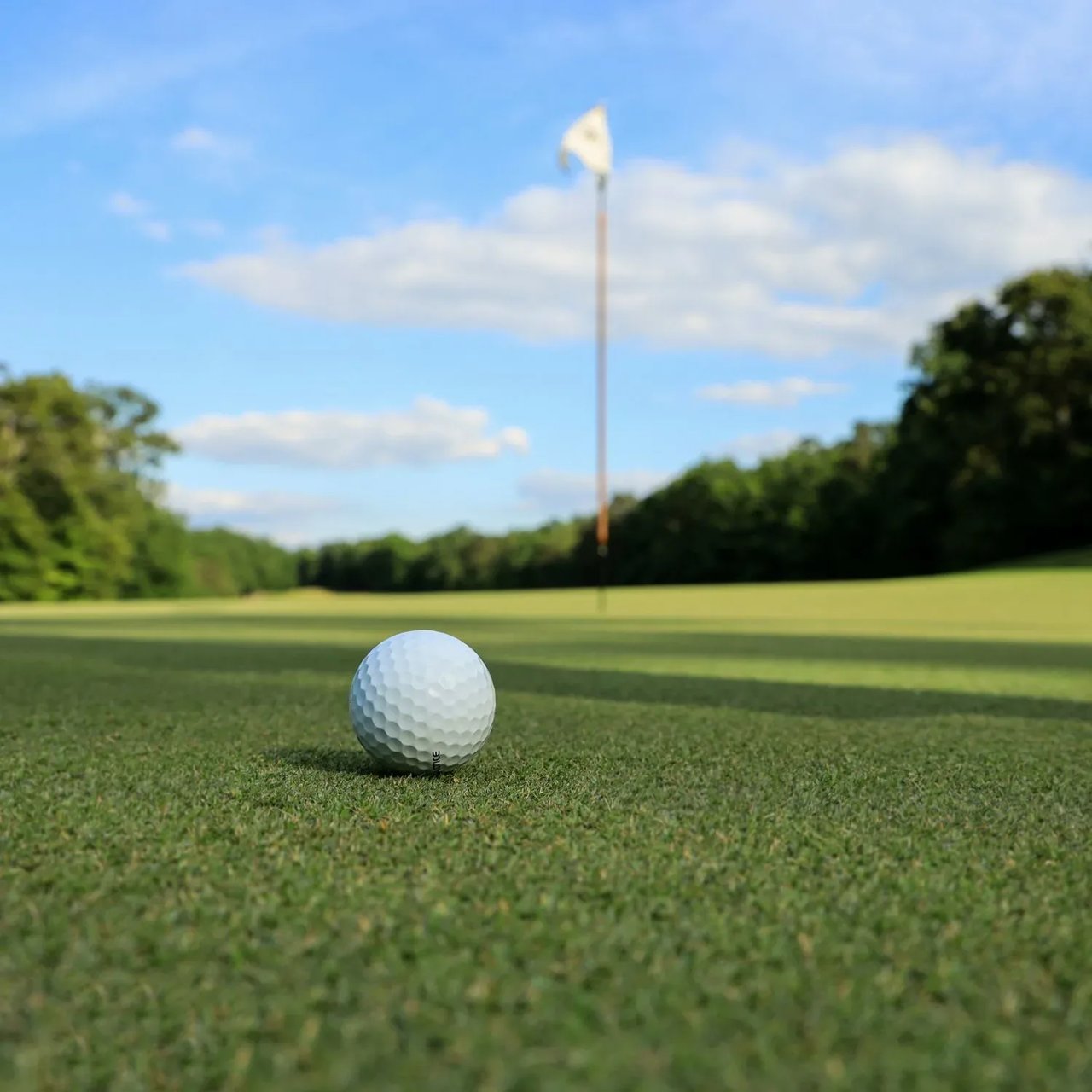 Golf ball on the vibrant green, moments from the hole, set against a backdrop of luxury estate serenity.