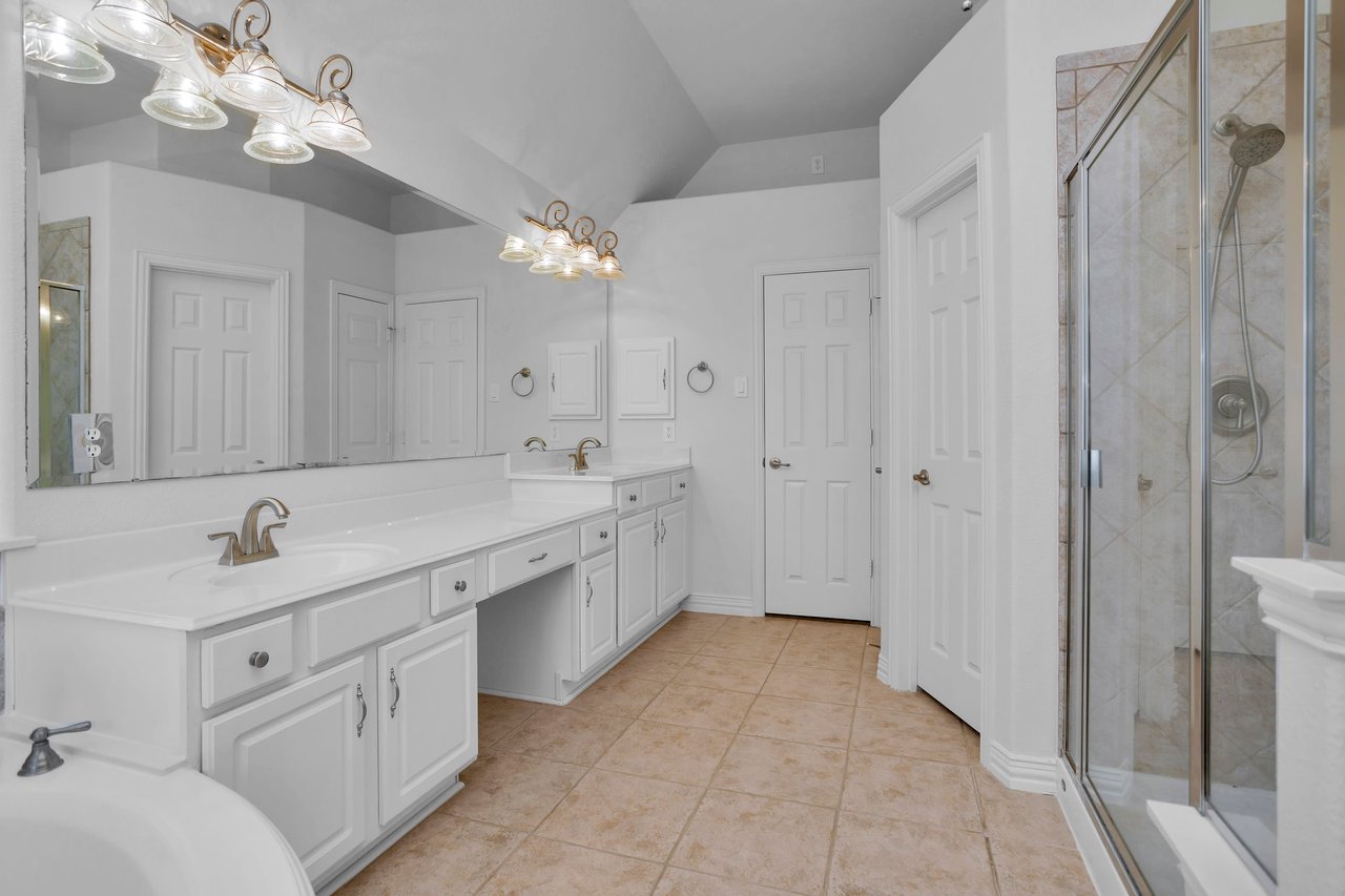 Primary bath with double sinks, vanity, walk-in closet, jetted tub and separate shower with bench seat. 