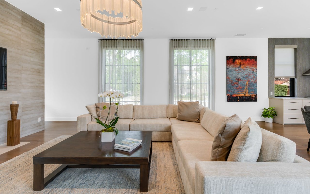 Stylish living room featuring a cozy white L-shaped sofa and an elegant round crystal chandelier.