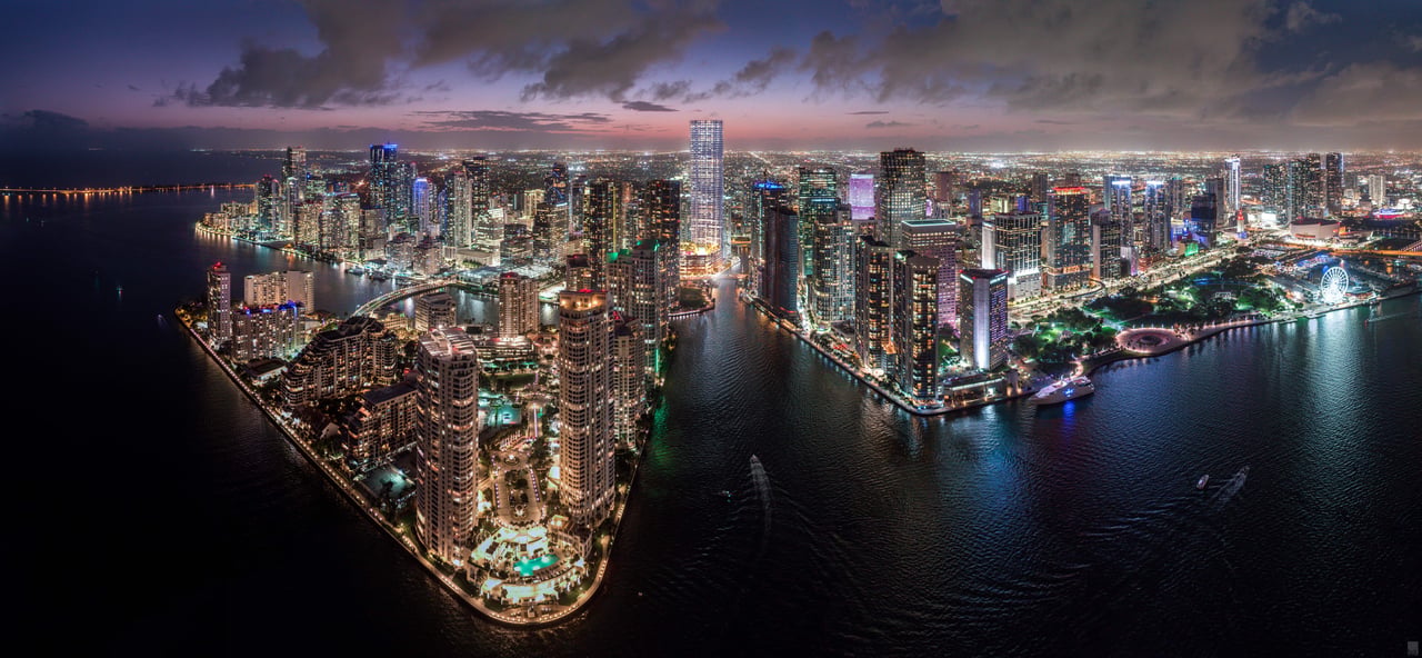 Aerial panorama of Miami’s waterfront skyline glowing at dusk across Biscayne Bay.