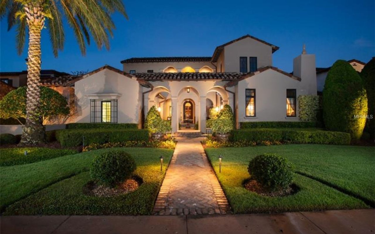 A large white house in Golden Oak with a lush front lawn, a walkway leading to the entrance, and trees on either side.