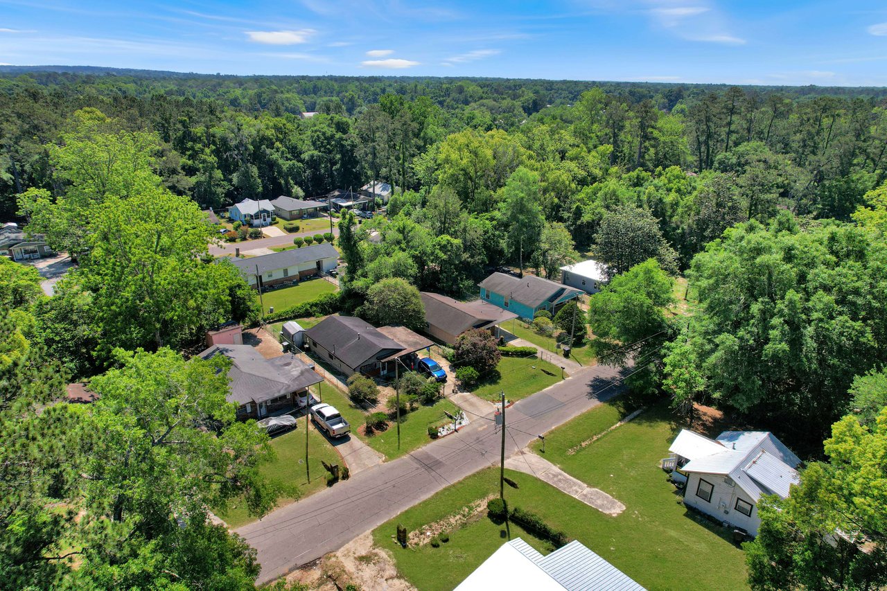 An aerial view of a residential neighborhood in Liberty Park showing houses with yards, tree-lined streets, and a well-maintained environment.