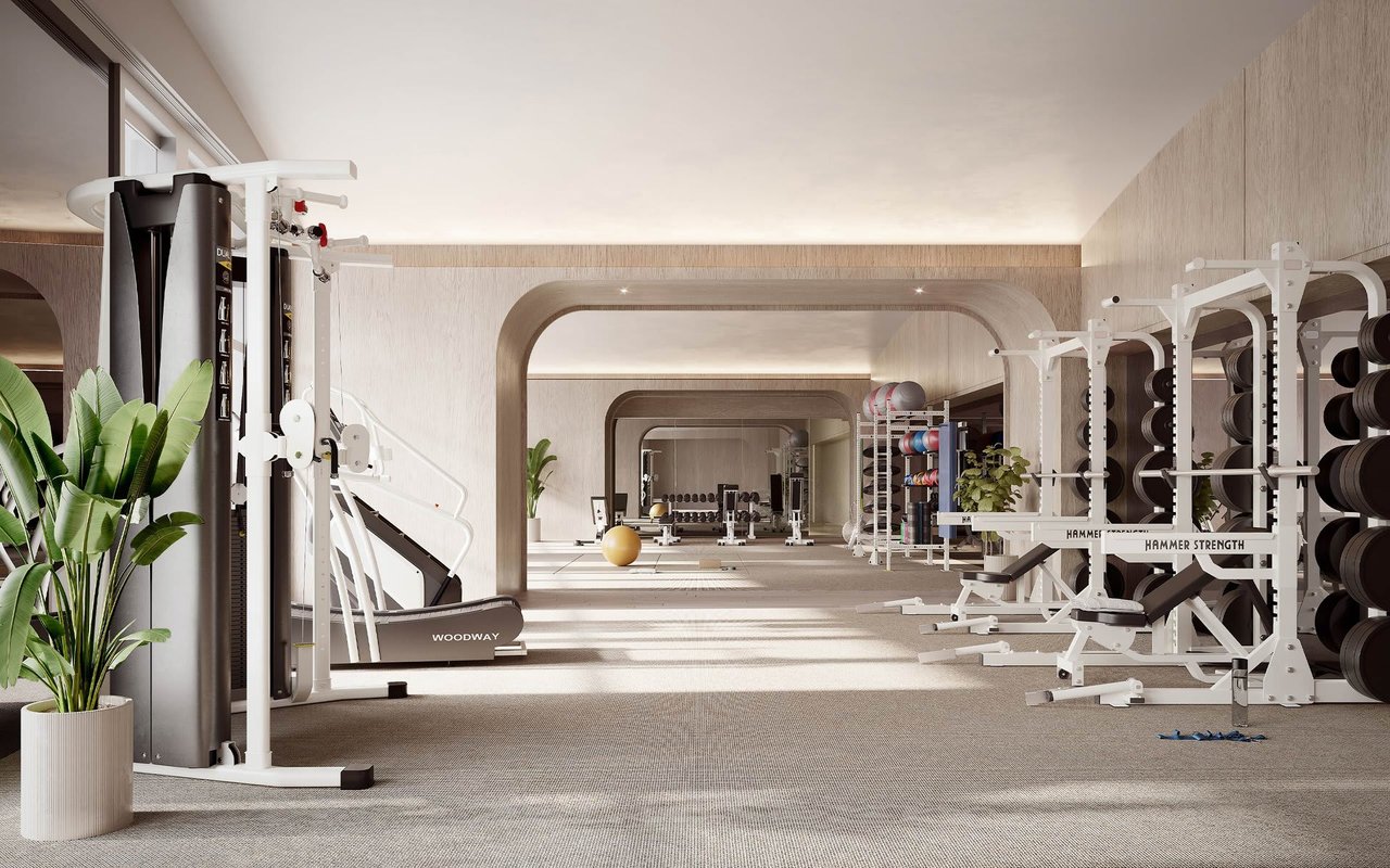 Fitness center with weight machines and free weights beneath rounded arches.