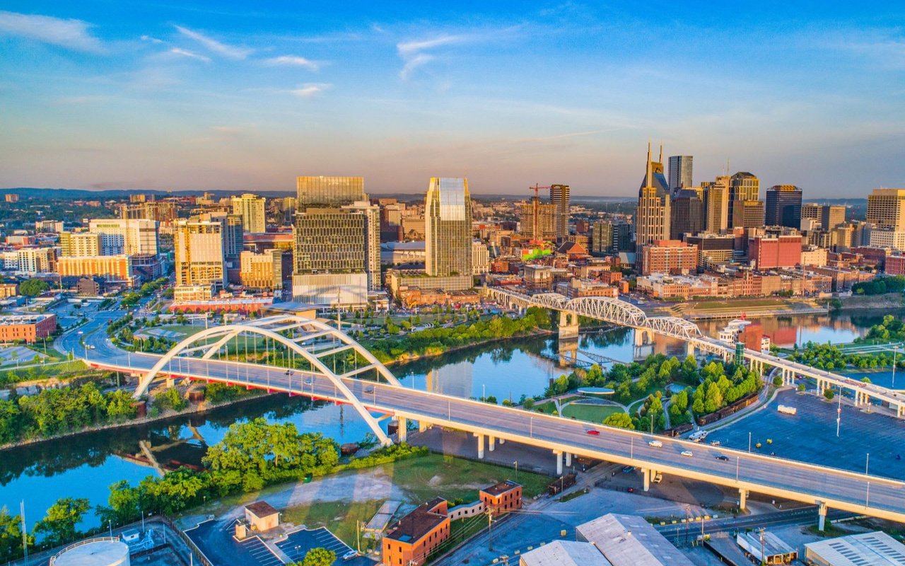 Aerial view of skyline with bridge over river at sunset.