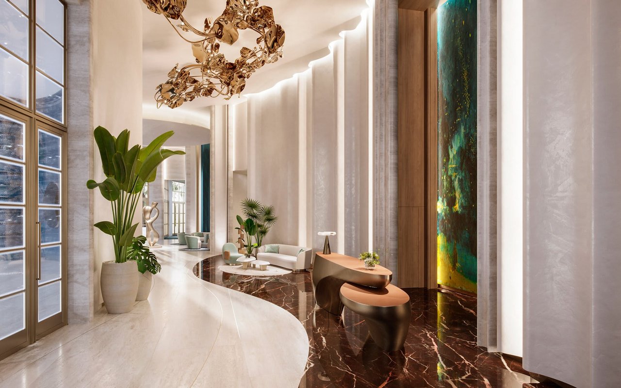 St. Regis Miami Residences lobby with marble floors, curved seating, tall windows, and a sculptural gold ceiling fixture.