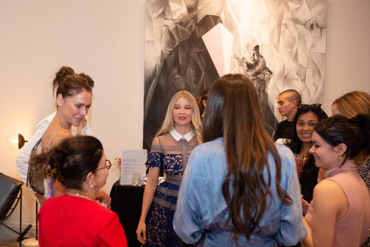 Guests mingle at an indoor event in front of a large abstract mural.