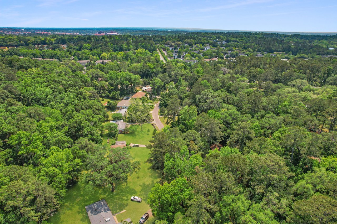 An aerial view of the Forest Heights Hollow community, showing houses nestled among dense greenery and forested areas.