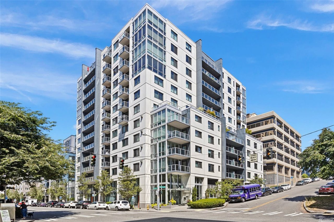 Modern high-rise condo building on a sunny day showcasing urban luxury living with a vibrant street scene.