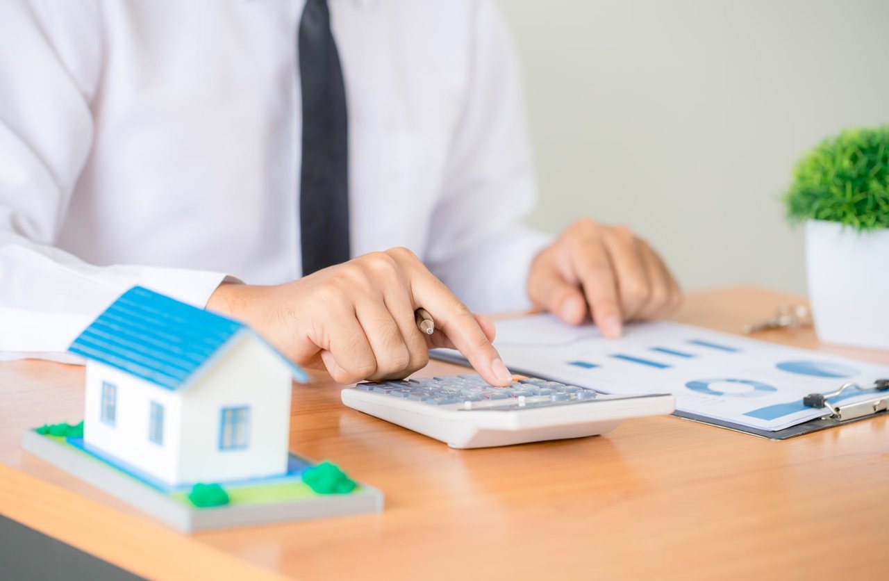 man is calculating beside a model house