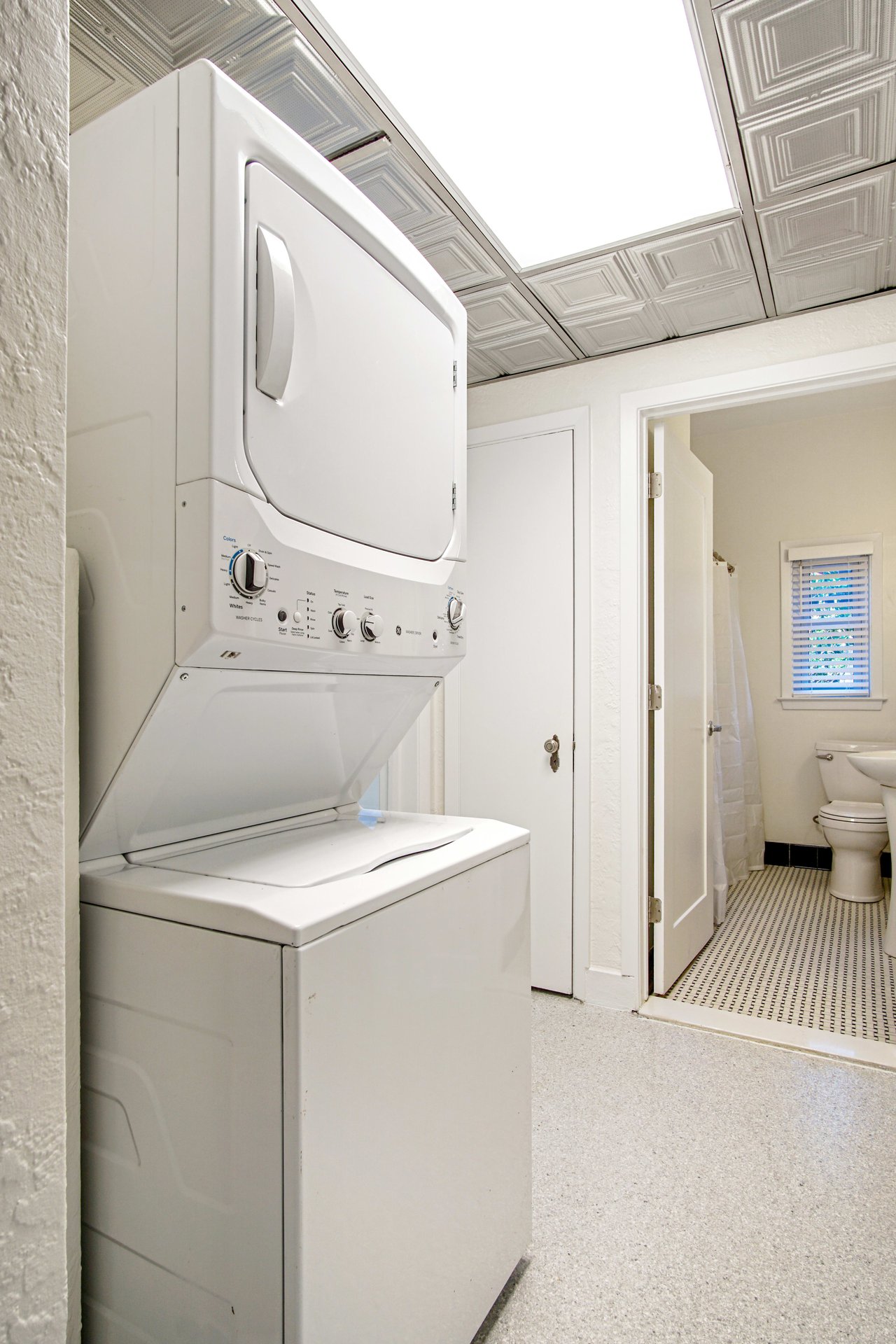 A laundry area with a stacked washer and dryer unit. The space appears functional and includes a small window for natural light.