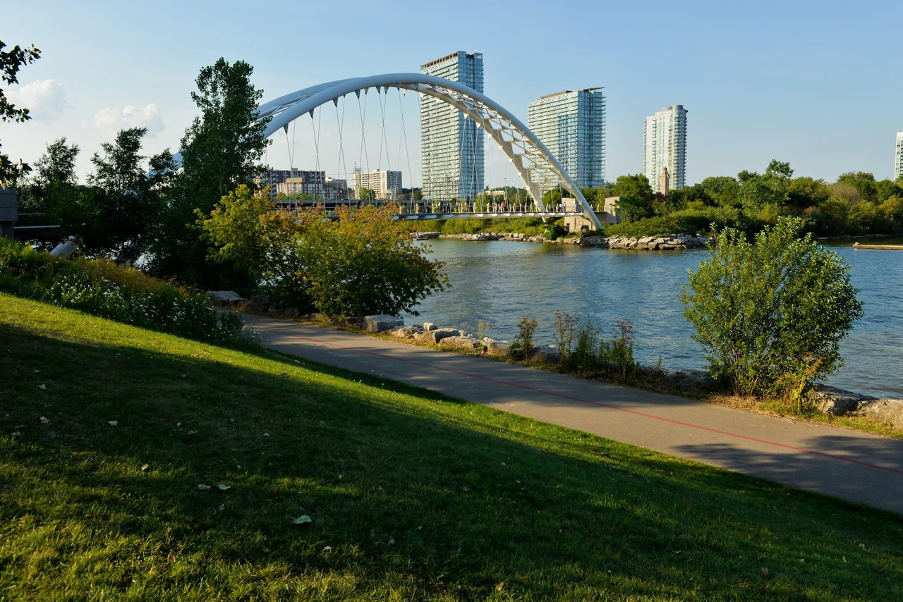 A suspension bridge towers over a body of water, with a city skyline in the distance