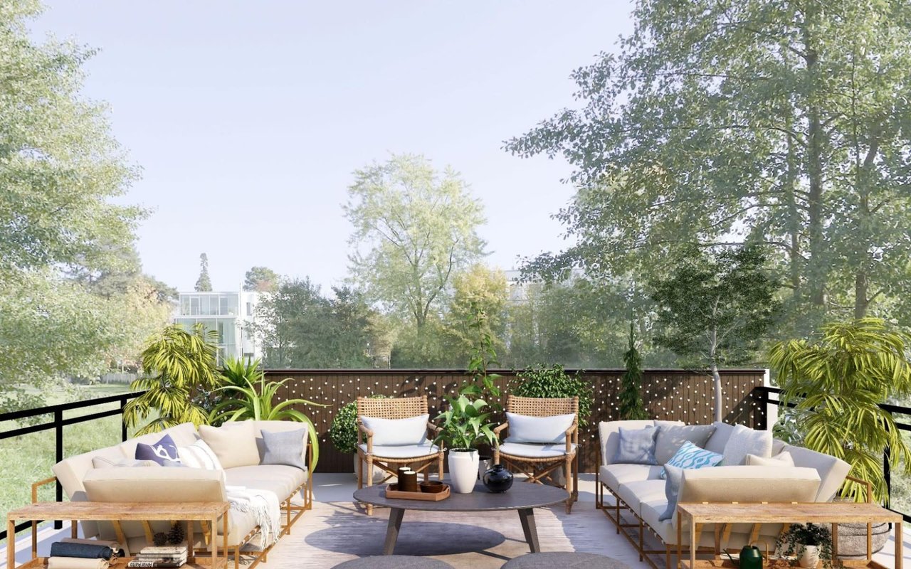  A beautifully furnished outdoor terrace, likely on a rooftop or elevated space, surrounded by lush green trees.