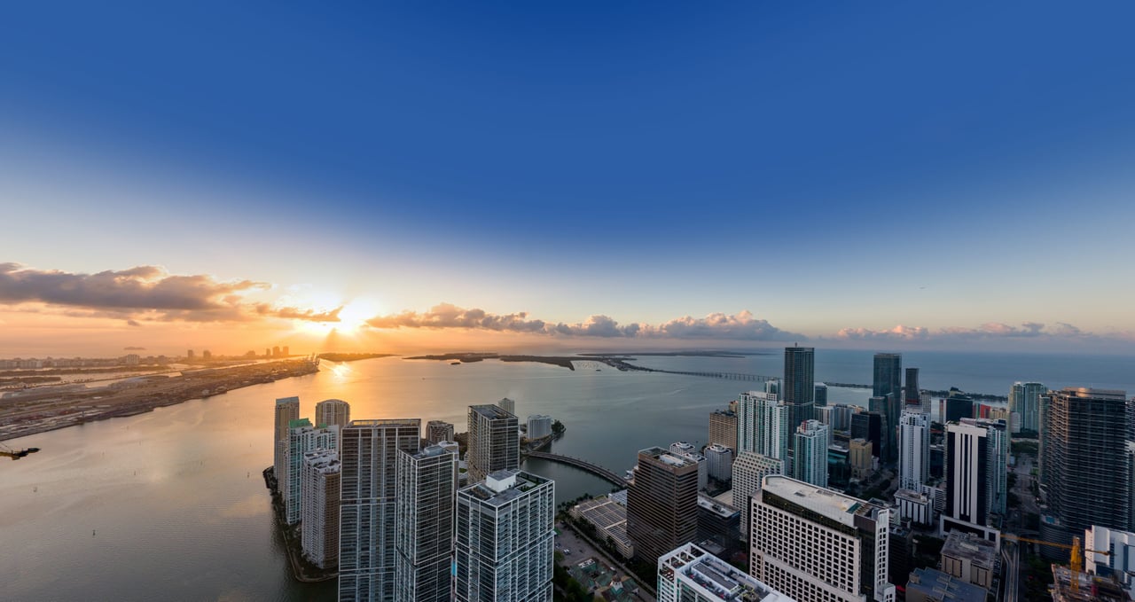 Waterfront city skyline and bay at sunset, seen from above.