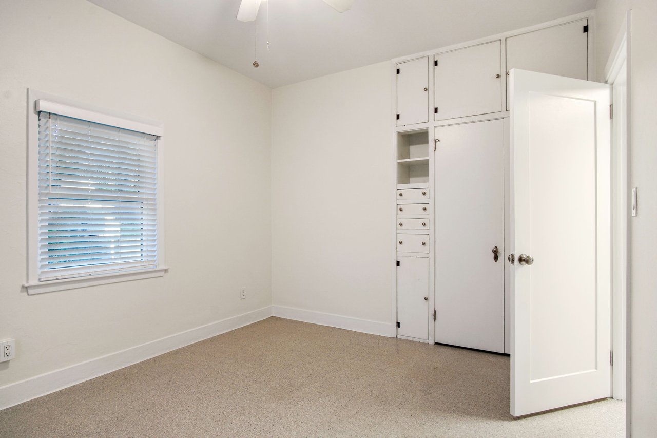 An interior shot of the third bedroom, featuring windows on two walls, built-in storage, and a neutral color scheme.