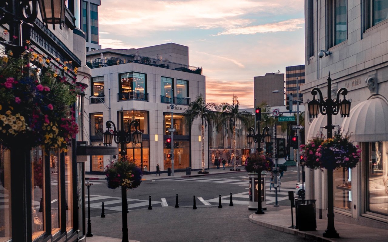 A city street with tall buildings and flowers on the sidewalk